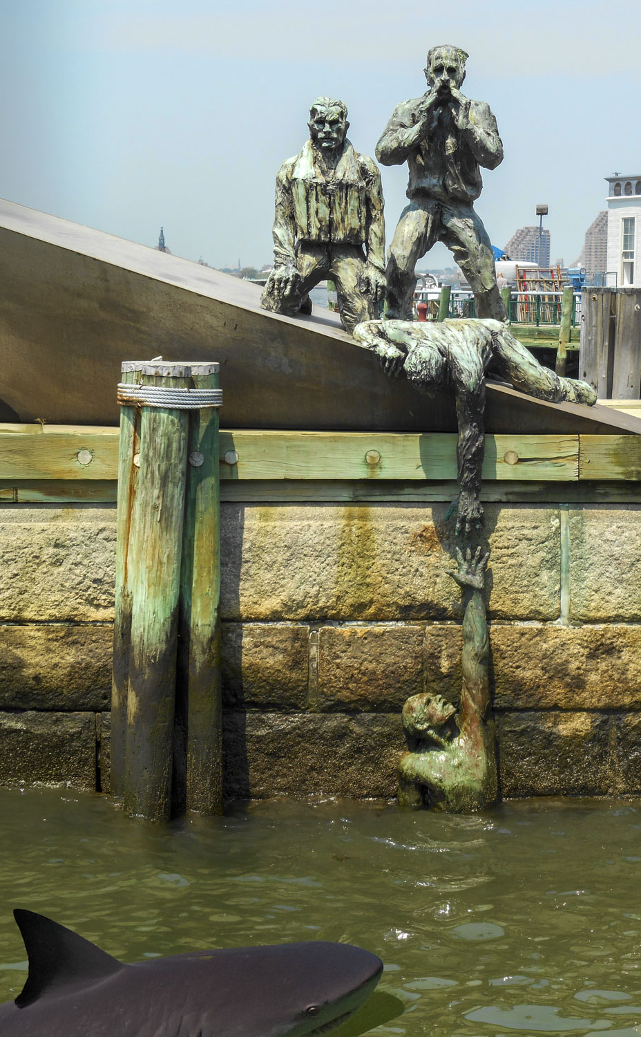 Battery Park NY statue of a man overboard with a shark fin swimming in the water
